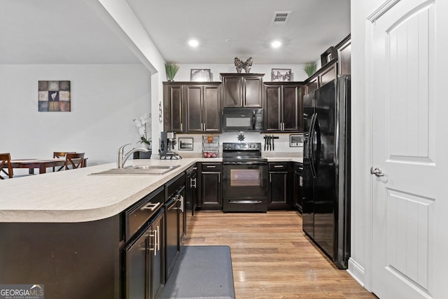 kitchen featuring light countertops, visible vents, a sink, light wood-style floors, and black appliances