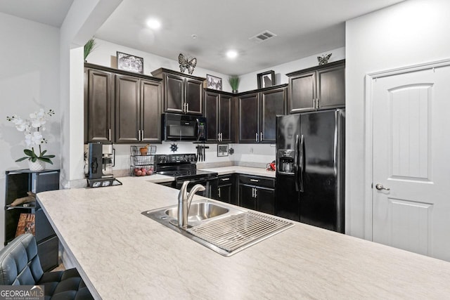 kitchen with light countertops, visible vents, dark brown cabinets, a breakfast bar area, and black appliances