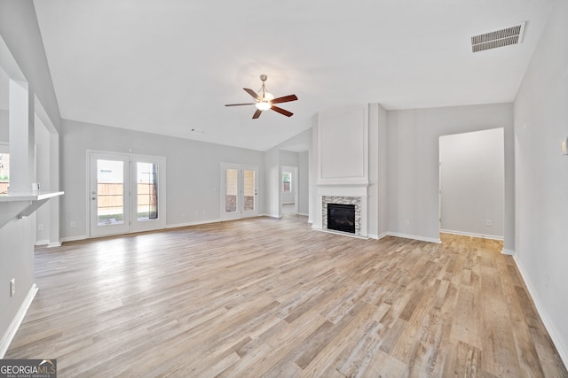 unfurnished living room featuring vaulted ceiling, a stone fireplace, visible vents, light wood-style floors, and ceiling fan