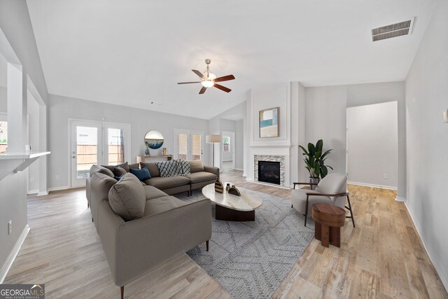 living room featuring lofted ceiling, ceiling fan, visible vents, and light wood-style floors