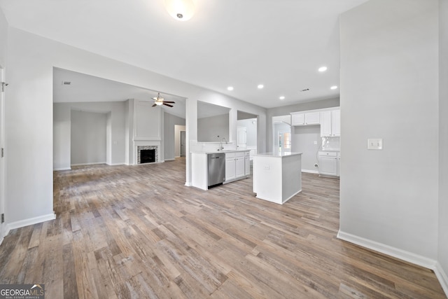 unfurnished living room featuring vaulted ceiling, a ceiling fan, light wood finished floors, a fireplace, and recessed lighting