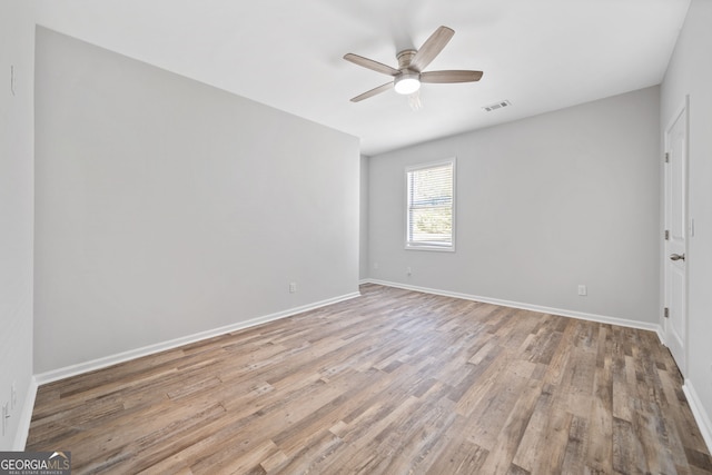 spare room featuring baseboards, visible vents, wood finished floors, and ceiling fan