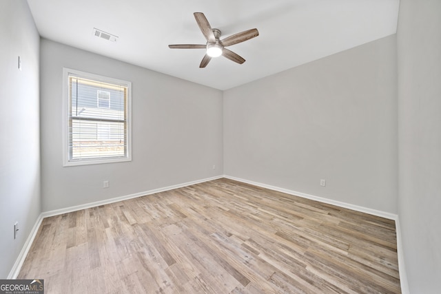 spare room with baseboards, visible vents, light wood-style floors, and a ceiling fan