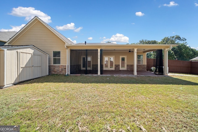 back of property with an outbuilding, a shed, fence, french doors, and stone siding