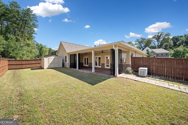 rear view of property with an outdoor structure, a shed, a fenced backyard, a ceiling fan, and a lawn
