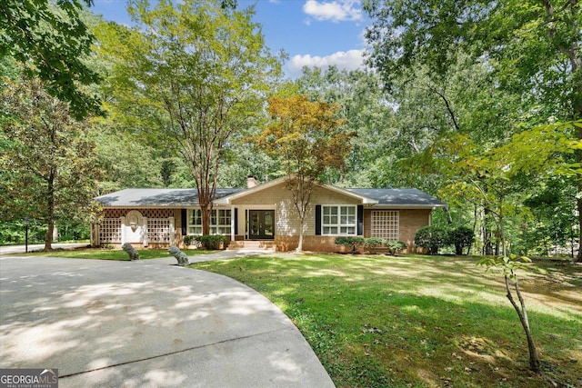ranch-style house featuring a porch, a chimney, and a front lawn