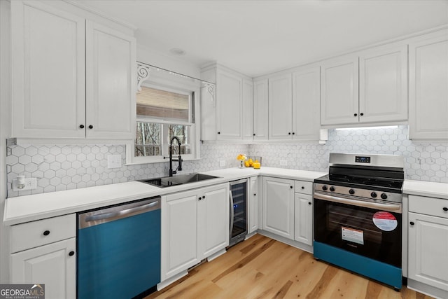 kitchen with stainless steel stove, light wood-style floors, wine cooler, dishwasher, and a sink