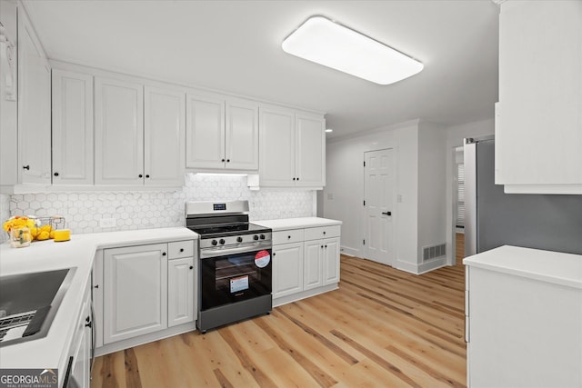 kitchen with stainless steel range with electric cooktop, light wood-style flooring, white cabinetry, visible vents, and decorative backsplash