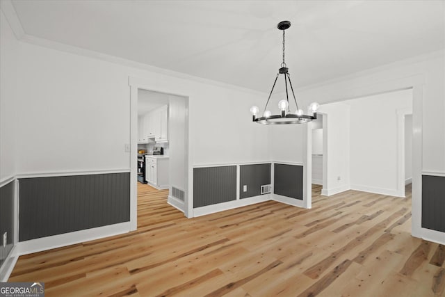 unfurnished dining area with a chandelier, light wood finished floors, and visible vents