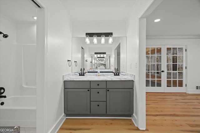 full bathroom with wood finished floors, double vanity, a sink, and shower / bathing tub combination