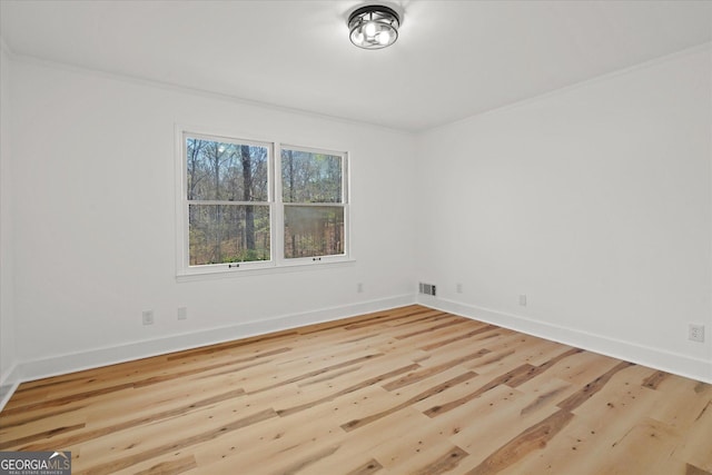 unfurnished room with visible vents, baseboards, wood finished floors, and ornamental molding