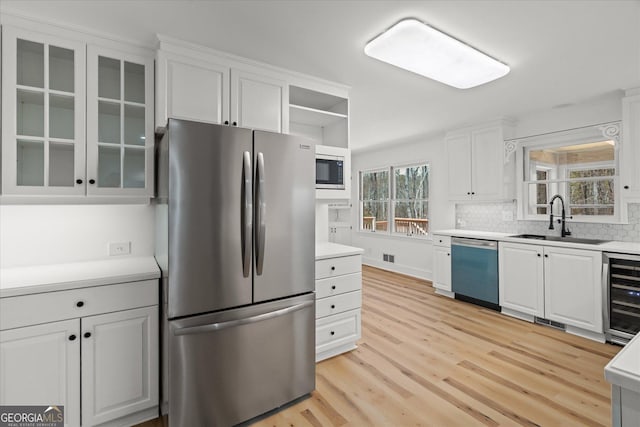 kitchen with freestanding refrigerator, built in microwave, wine cooler, dishwasher, and a sink