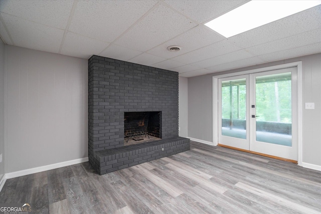 unfurnished living room with visible vents, baseboards, a paneled ceiling, a fireplace, and wood finished floors