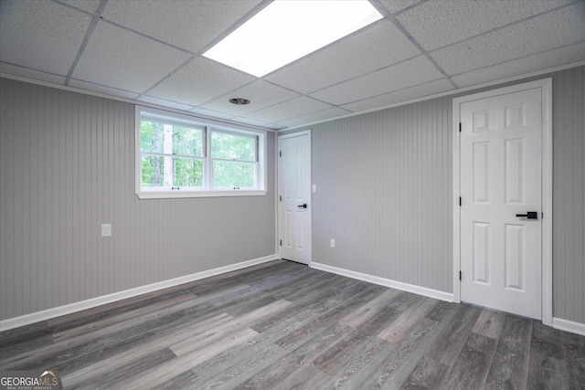 empty room with a drop ceiling, baseboards, and wood finished floors