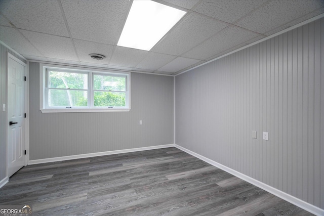 unfurnished room featuring wood finished floors, baseboards, a drop ceiling, and visible vents