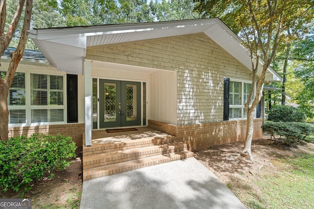 view of exterior entry featuring brick siding and french doors