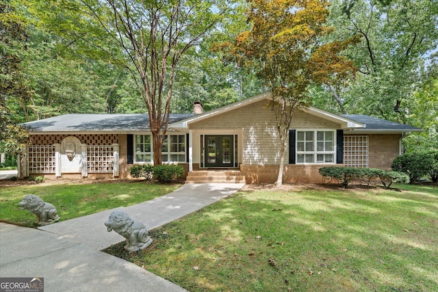 ranch-style house with a front yard, french doors, brick siding, and a chimney