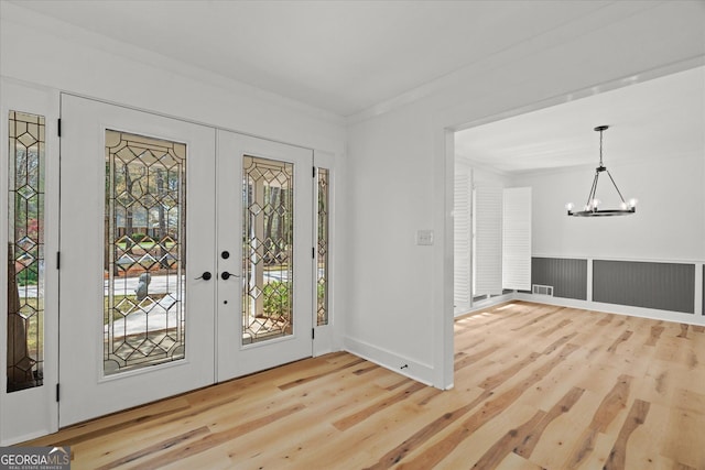 entrance foyer with french doors, visible vents, an inviting chandelier, and wood finished floors