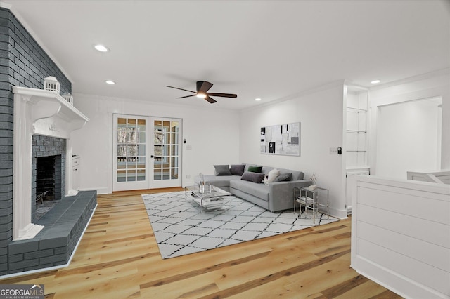 living room with ornamental molding, ceiling fan, a brick fireplace, and wood finished floors