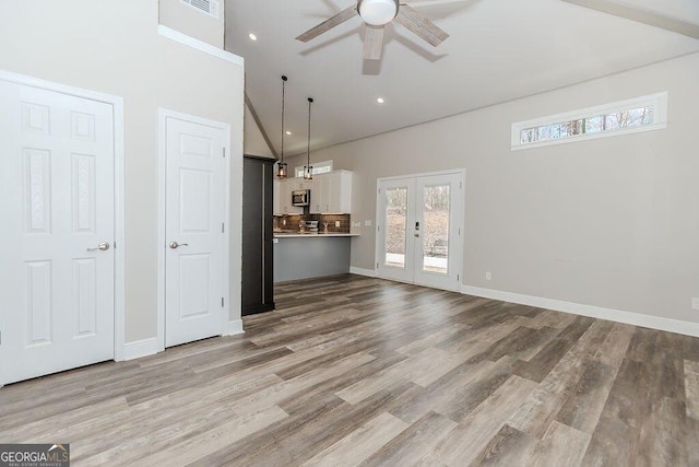 4660 Perry Rd, Gainesville, GA 30506 - unfurnished living room featuring a ceiling fan, healthy amount of natural light, high vaulted ceiling, wood finished floors, and french doors