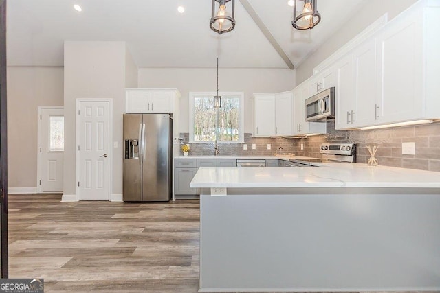 4660 Perry Rd, Gainesville, GA 30506 - kitchen with stainless steel appliances, lofted ceiling, light countertops, backsplash, and hanging light fixtures