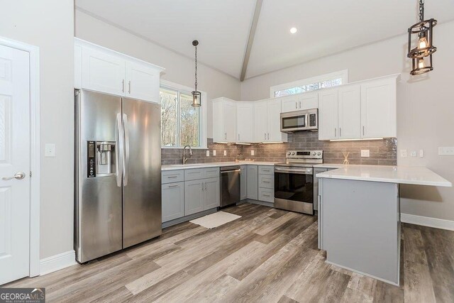 4660 Perry Rd, Gainesville, GA 30506 - kitchen featuring appliances with stainless steel finishes, decorative backsplash, light wood finished floors, vaulted ceiling, and recessed lighting