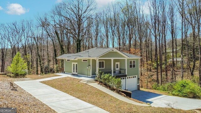 4660 Perry Rd, Gainesville, GA 30506 - view of front of home featuring concrete driveway, an attached garage, a view of trees, and a porch