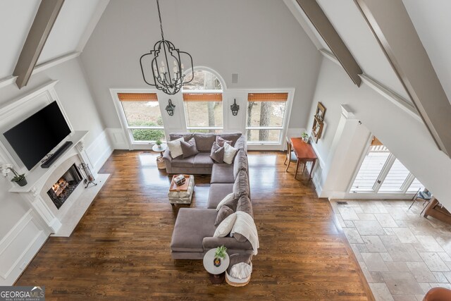 275 Tynebrae Pl, Roswell, GA 30075 - living room with high vaulted ceiling, a decorative wall, beamed ceiling, a chandelier, and a warm lit fireplace