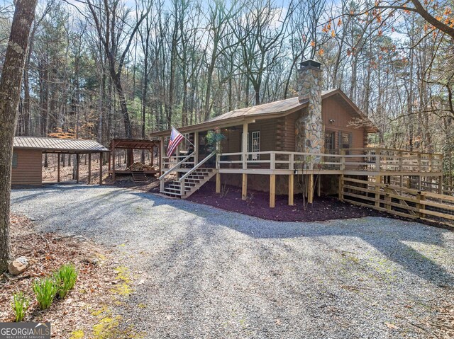 335 Misty Hollow Rd, Ellijay, GA 30536 - view of front of house featuring log exterior, a chimney, a wooden deck, metal roof, and gravel driveway