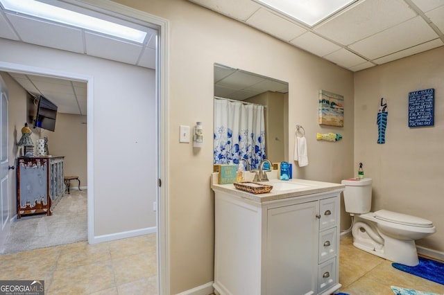 667 Cardinal Dr, Monticello, GA 31064 - bathroom featuring a drop ceiling, toilet, vanity, and baseboards
