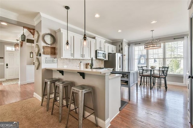 5753 Porch Swing Pl, Hoschton, GA 30548 - kitchen featuring stainless steel appliances, healthy amount of natural light, crown molding, light wood-type flooring, and tasteful backsplash