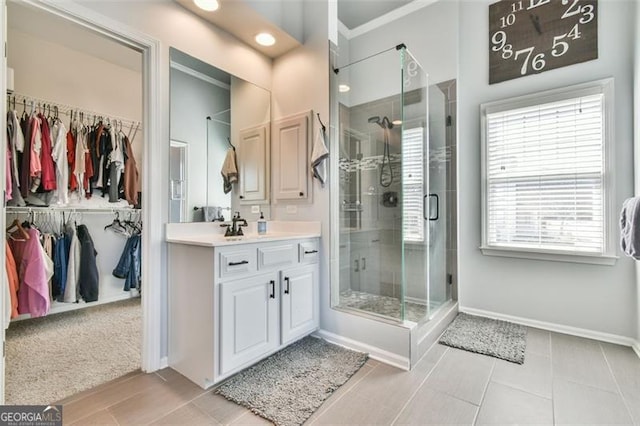 5753 Porch Swing Pl, Hoschton, GA 30548 - full bath with vanity, a stall shower, a walk in closet, baseboards, and crown molding