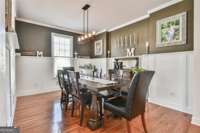 5753 Porch Swing Pl, Hoschton, GA 30548 - dining space with a decorative wall, a chandelier, wood finished floors, crown molding, and wainscoting