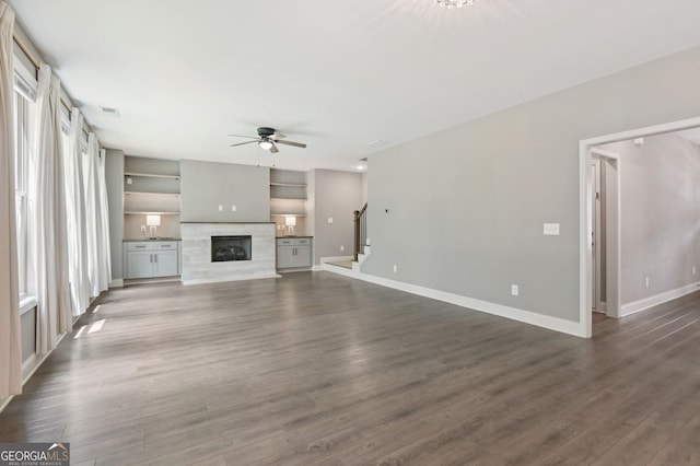 557 Winder Trl, Canton, GA 30114 - unfurnished living room featuring ceiling fan, stairs, a glass covered fireplace, and dark wood-type flooring