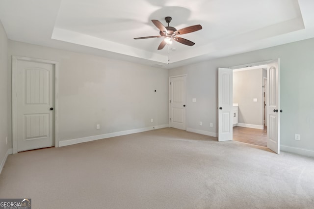 557 Winder Trl, Canton, GA 30114 - unfurnished bedroom featuring a tray ceiling, light colored carpet, and ceiling fan