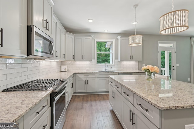 557 Winder Trl, Canton, GA 30114 - kitchen featuring appliances with stainless steel finishes, a chandelier, a kitchen island, dark wood-type flooring, and light stone countertops