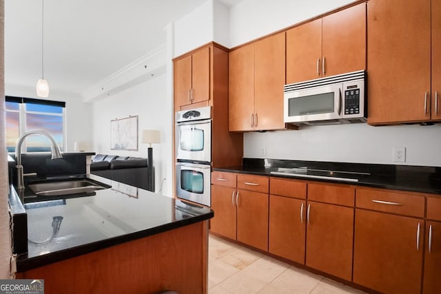 kitchen featuring a sink, appliances with stainless steel finishes, brown cabinetry, and dark countertops