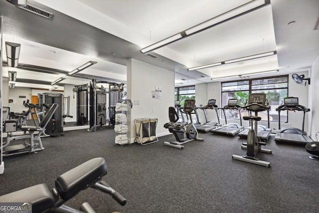 exercise room with a tray ceiling and visible vents