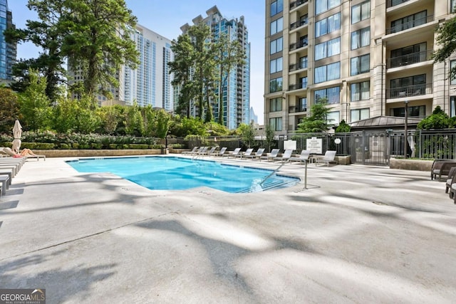 pool featuring a patio, fence, and a city view