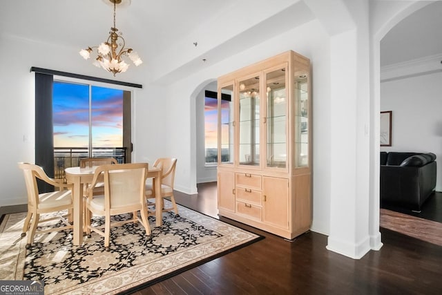 dining space featuring a wealth of natural light, baseboards, dark wood-type flooring, arched walkways, and a notable chandelier