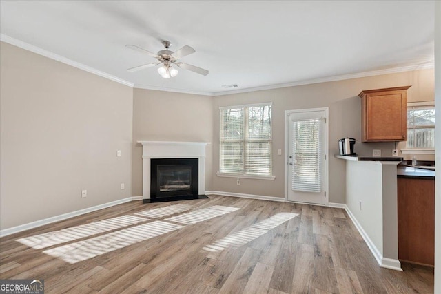 145 Sunset Ln, Woodstock, GA 30189 - unfurnished living room featuring healthy amount of natural light, light wood-style floors, ceiling fan, baseboards, and crown molding