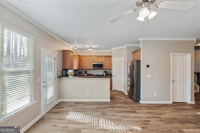 145 Sunset Ln, Woodstock, GA 30189 - kitchen featuring stainless steel appliances, ornamental molding, a ceiling fan, light wood-style flooring, and a peninsula