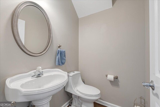 145 Sunset Ln, Woodstock, GA 30189 - half bath featuring a sink, toilet, baseboards, and vaulted ceiling