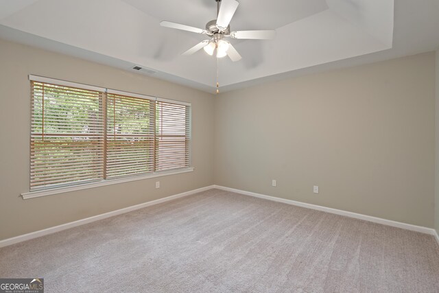 145 Sunset Ln, Woodstock, GA 30189 - spare room with light colored carpet, baseboards, ceiling fan, and a tray ceiling