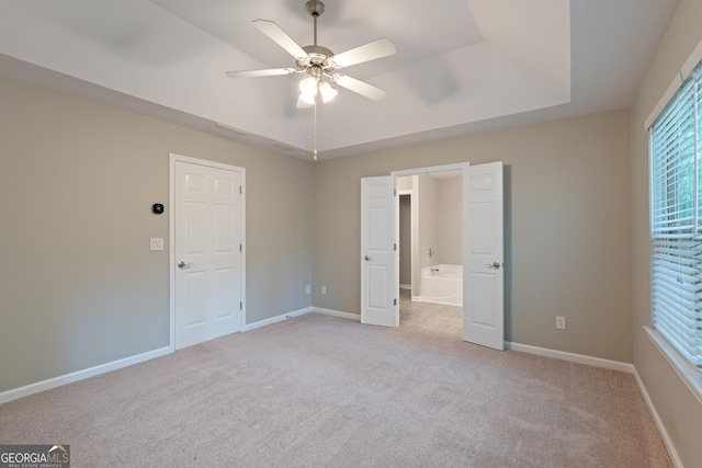 145 Sunset Ln, Woodstock, GA 30189 - unfurnished bedroom with a tray ceiling, light carpet, multiple windows, and baseboards