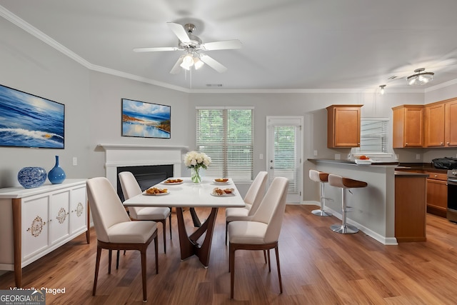 145 Sunset Ln, Woodstock, GA 30189 - dining room featuring a ceiling fan, light wood-style floors, a fireplace, and crown molding