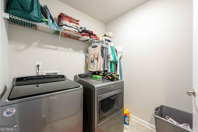 clothes washing area featuring baseboards, laundry area, and washer and clothes dryer