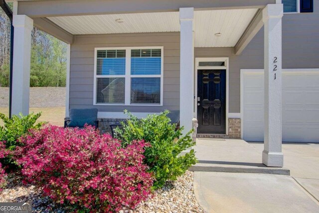 221 Sullivan St, Hampton, GA 30228 - doorway to property with stone siding, covered porch, and an attached garage
