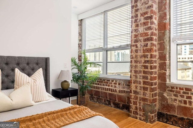 bedroom with wood finished floors and brick wall