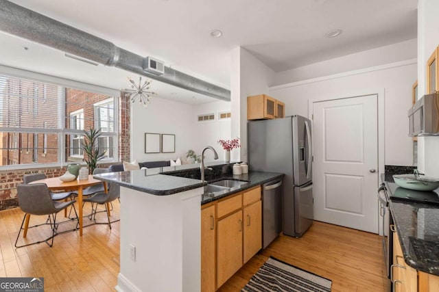 kitchen featuring a sink, light wood-style floors, visible vents, a peninsula, and appliances with stainless steel finishes